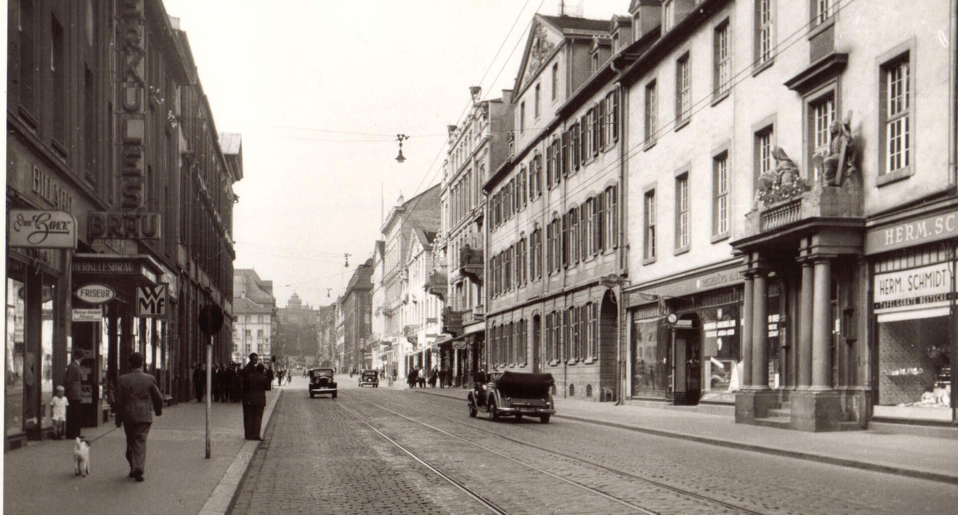 Historische Aufnahme einer Kasseler Geschäftsstraße mit Straßenbahngleisen, rechts das Geschäft „Herm. Schmidt“