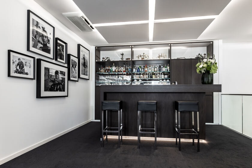 Bar mit Barhockern im Ladengeschäft, an der Wand gerahmte Schwarz-Weiß-Fotografien