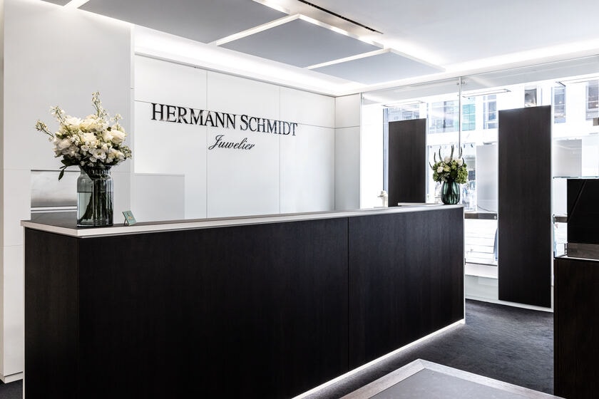 Empfangstresen mit Blumenstrauß vor dem Schriftzug Hermann Schmidt Juwelier