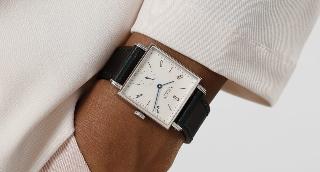 Eckige Armbanduhr mit weißem Zifferblatt an einem Handgelenk