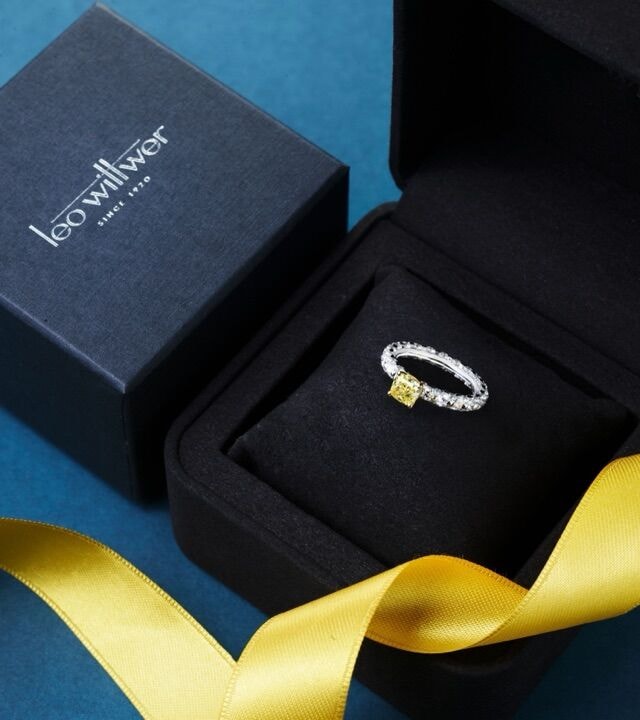 Ring mit gelbem Diamanten in einem geöffneten Leo-Wittwer-Etui mit gelbem Satinband