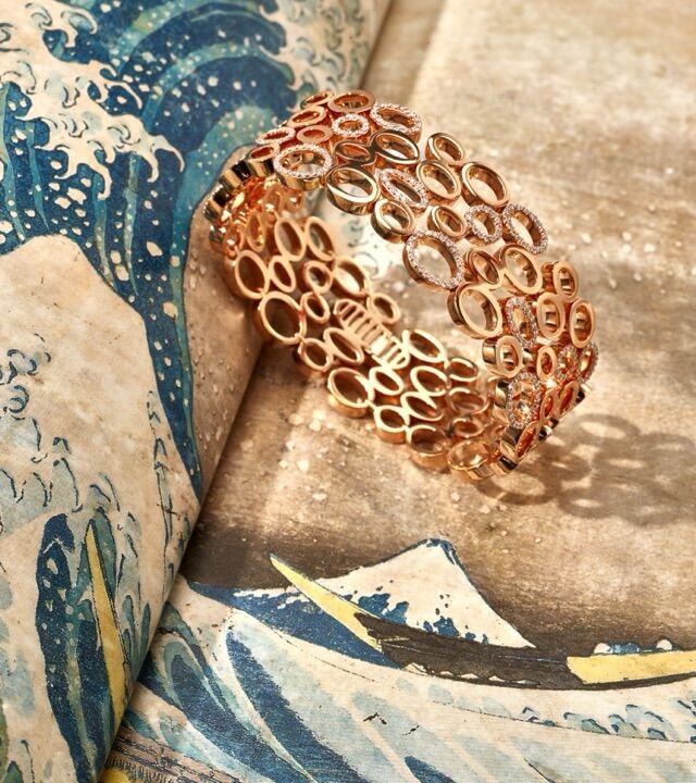 Armreif der Linie Panta rhei aus Roségold-Kreisen auf einem Druck von Hokusais „Großer Welle“